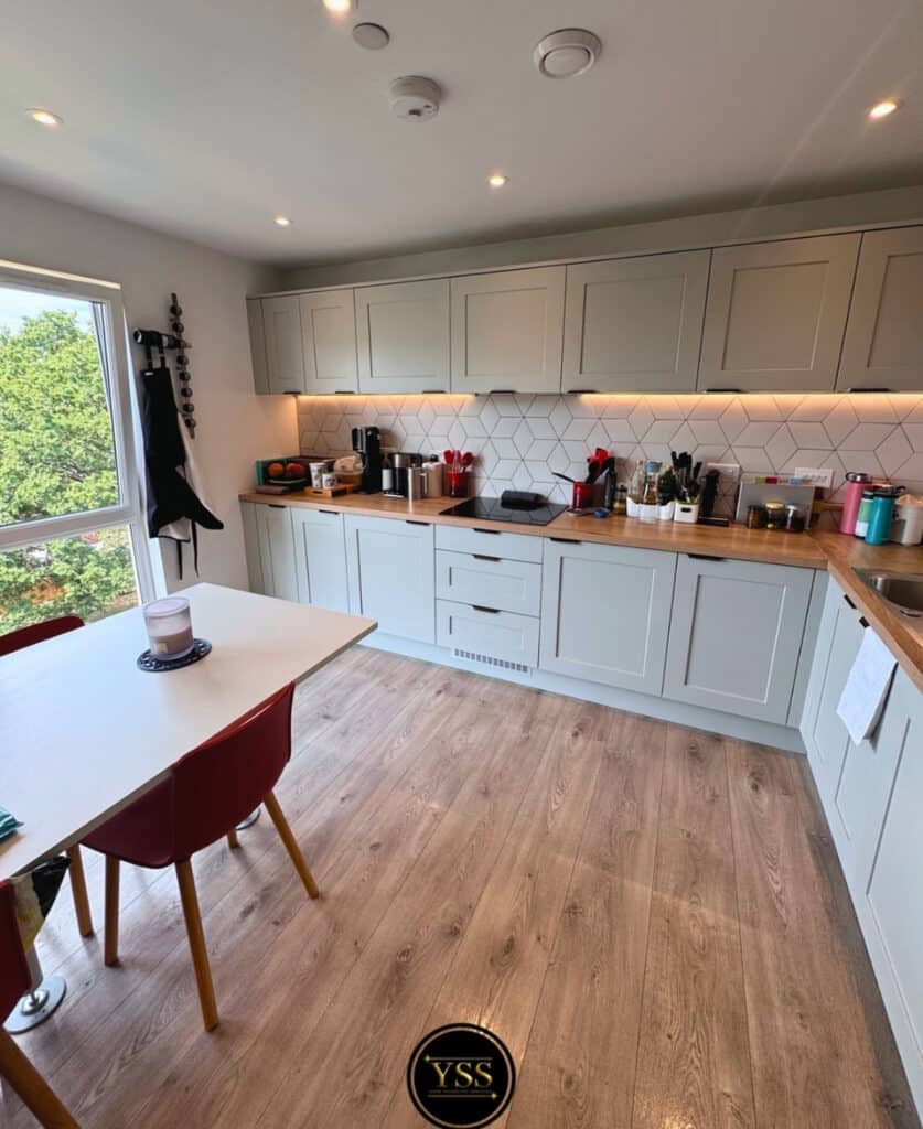 Shiny modern kitchen with grey cabinets, wooden worktops, and natural light. Perfect for cleaning and home upkeep.