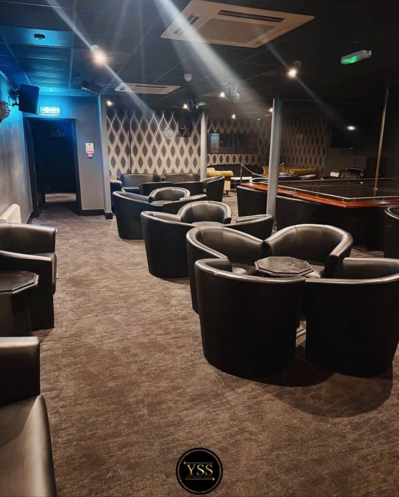 Polished lounge with black leather chairs and stylish patterned wallpaper for comfortable seating.