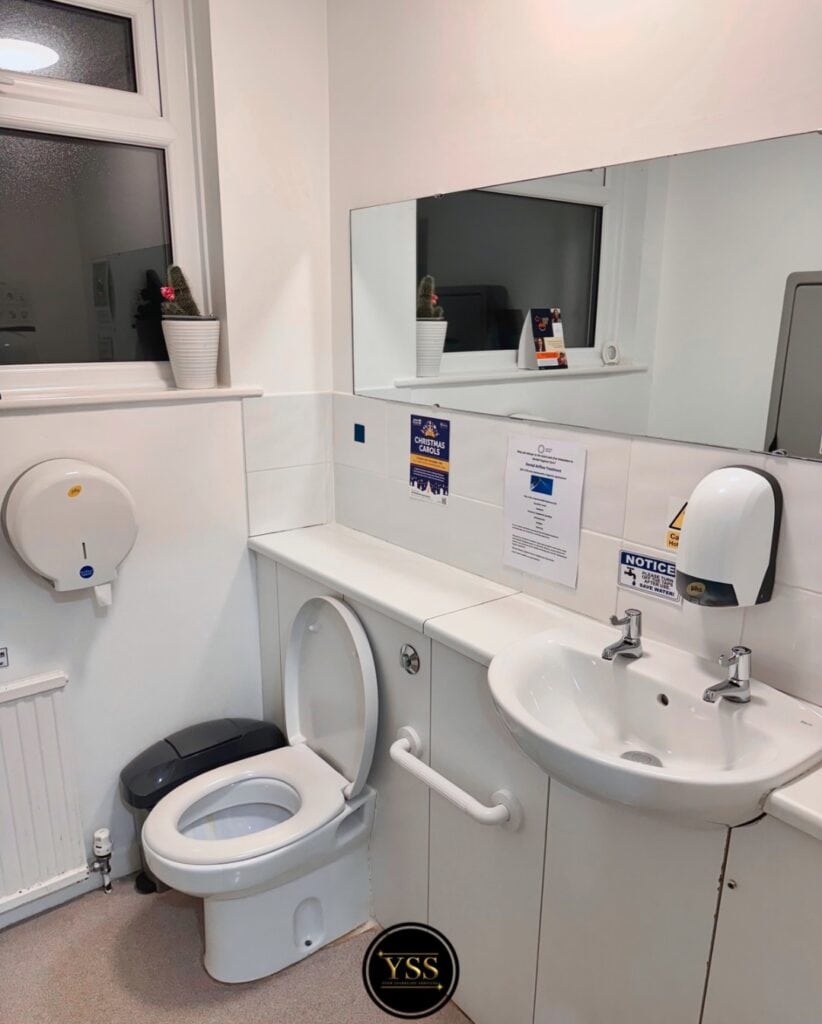 Clear cleaning of bathroom facilities, including toilet, sink, and hand dryer for hygienic spaces.