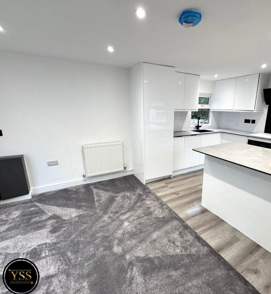 Polished grey carpet in modern white kitchen with sleek cabinetry and island, bright and contemporary interior design.