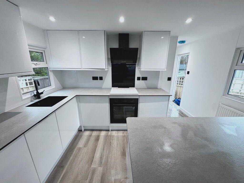Sparkling kitchen with modern white cabinets and black appliances, showcasing professional cleaning services.