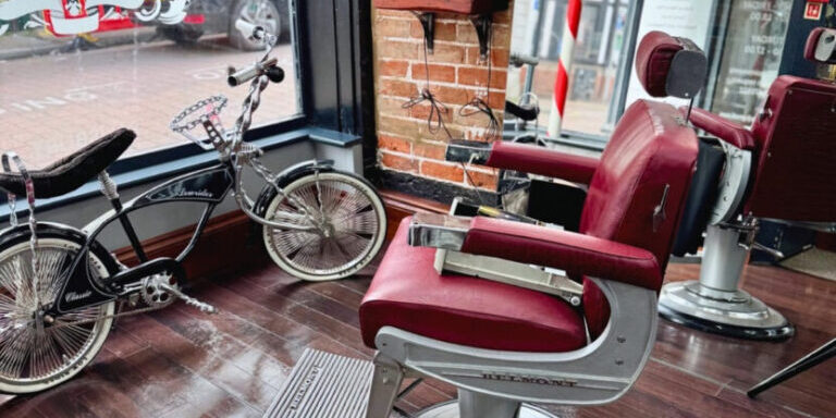 Shaving barber chair in modern salon with wooden flooring and large window.
