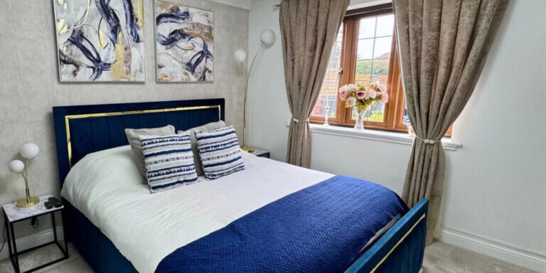 Bright modern bedroom with polished hardwood flooring, elegant curtains, and contemporary wall art.